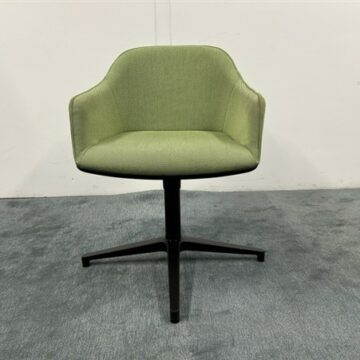 A modern green upholstered swivel chair with a curved backrest and black four-legged base, placed on a gray carpeted floor against a plain white wall.